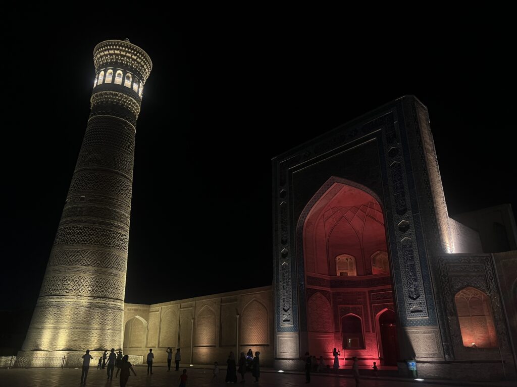 Night view of the illuminated Kalyan Minaret and Po-i-Kalyan Mosque in Bukhara, Uzbekistan, showcasing intricate Islamic architecture against a dark sky.